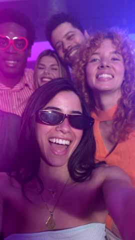 Nightclub party featuring diverse friends capturing moments, sharing excitement, dancing with infectious joy amid vibrant music and energetic atmosphere