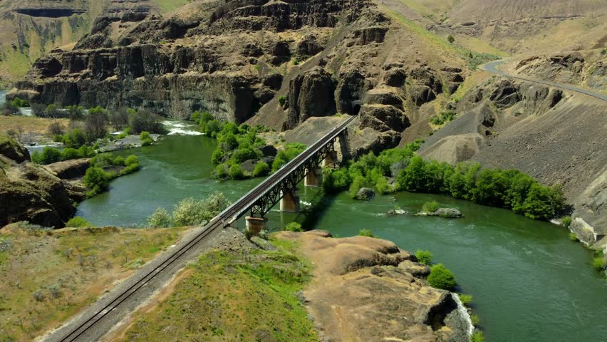 US, Oregon, Maupin, Deschutes River, 2025-05-08 - Drone view on the Deschutes River of a train bridge at Twin Crossings which is two bridges and a tunnel. In north central Oregon in spring