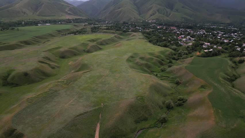 A hilly area with different vegetation and a river. Cloudy weather, spring. The view from the drone.