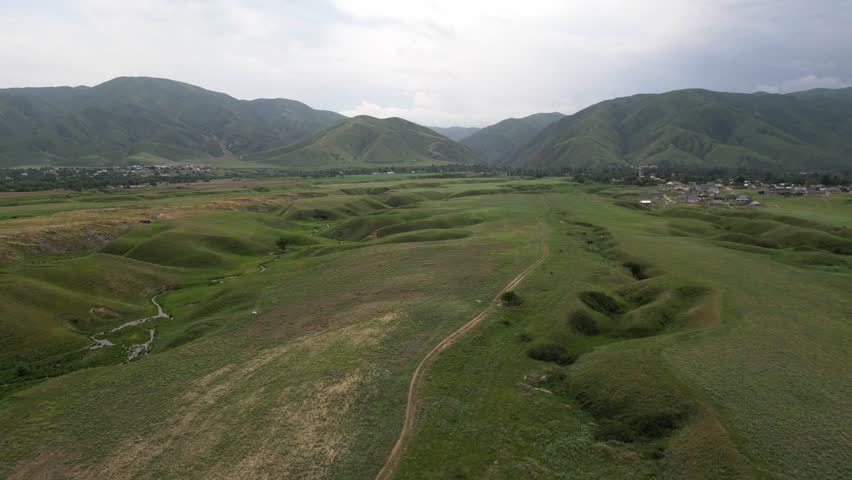 A hilly area with different vegetation and a river. Cloudy weather, spring. The view from the drone.