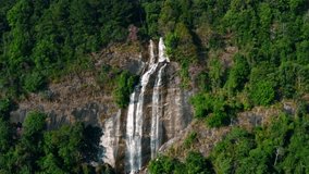 Aerial drone footage captures majestic waterfall cascading down rocky cliffs in Doi Inthanon surrounded by lush greenery and vibrant foliage, showcasing nature's beauty - Powered by Shutterstock - Get 15% off with code: PIKWIZARD15