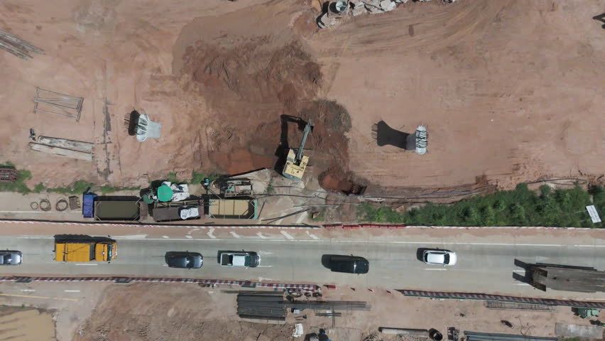 Drone shot of highway and overpass construction site with vehicles, roads. Ideal for infrastructure, civil engineering, or transportation themes