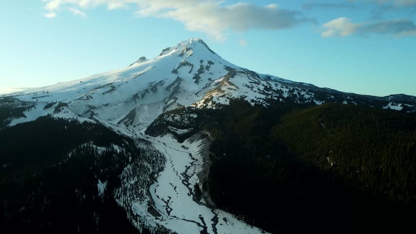 US, Oregon, Mt Hood, White River, 2025-04-22 - Drone view of Mt Hood at sunset over the White River in spring, with snow still covering the mountain and creek and trees