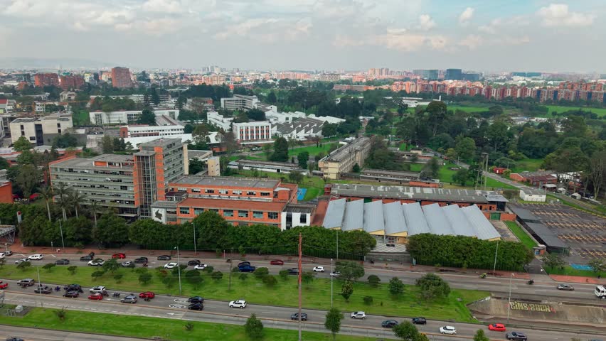 Aerial orbit establishing the headquarters of the National University of Colombia on a sunny day with the city and its architecture in the background.