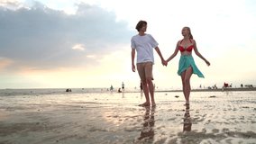 Romantic white Western couple walking and playfully teasing each other along the beach at sunset. Joyful and loving moment captured during golden hour by the sea, filled with warmth and affection. - Powered by Shutterstock - Get 15% off with code: PIKWIZARD15