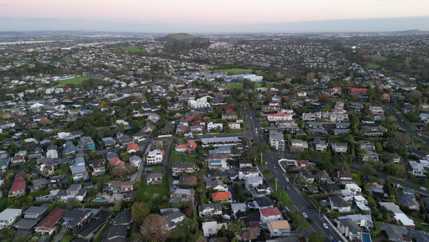 Sunset drone view of Mt Wellington rising beyond Auckland homes and streets, New Zealand