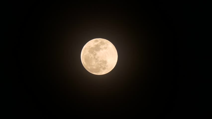 Bright orange and yellow full moon set against dark black sky