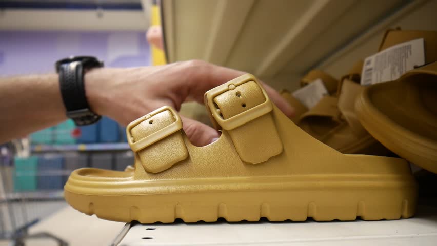 Close-up of a male customer's hand taking beach sandals from a store shelf