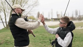 Dad took his son fishing on Father's Day. Happy son greets his father with a high five. Fatherhood concept. - Powered by Shutterstock - Get 15% off with code: PIKWIZARD15