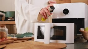 Woman adding oil and closing modern air fryer preparing food in kitchen - Powered by Shutterstock - Get 15% off with code: PIKWIZARD15