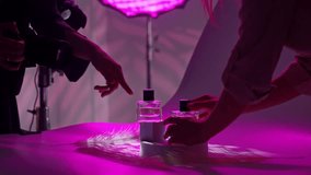 Backstage. A photographer and designer capture perfume bottles in a purple-lit studio, focusing on the perfect shot. - Powered by Shutterstock - Get 15% off with code: PIKWIZARD15