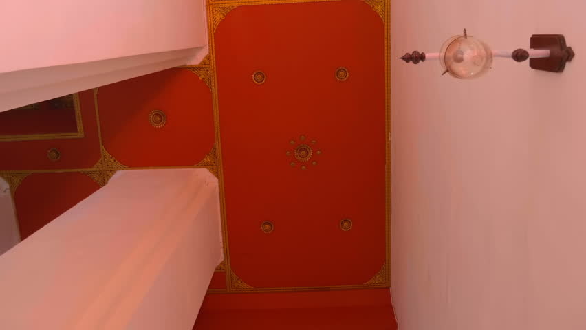 Tall white columns support a red ceiling with lamps in an Asian temple