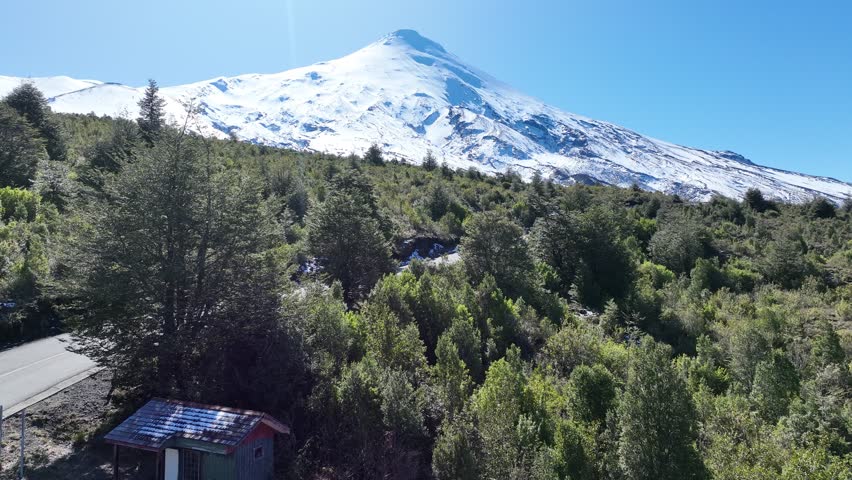 Osorno Vulcan In Osorno Los Lagos Chile. Snow-Capped Volcano Releasing Plumes Of Smoke Into Blue Sky. Snowflakes Lake Glacial Snow Mountain. Snowflakes Nature. Osorno Los Lagos.