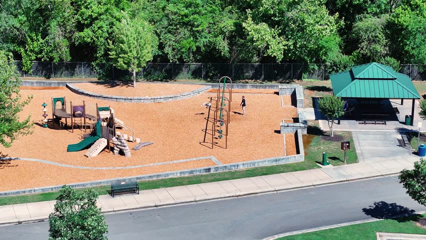 aerial footage of a man pushing his child in a swing on the playground at Etowah River Park in Canton Georgia USA