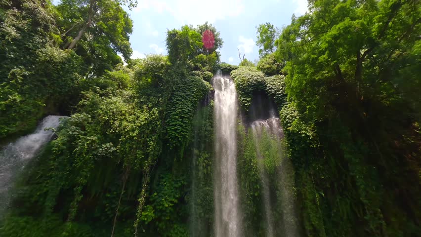 Cinematic FPV drone flight through cascading waters of Sekumpul Waterfall, surrounded by lush green jungle in Bali, Indonesia. Ideal for nature, travel, and tropical adventure themes.