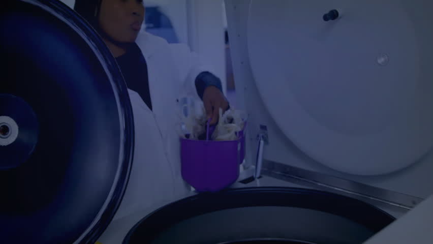 Lab tech securing purple rack into centrifuge, animating overlay showing data flow prepping samples. Science, research, technology, laboratory, innovation, digital, precision - Powered by Shutterstock - Get 15% off with code: PIKWIZARD15