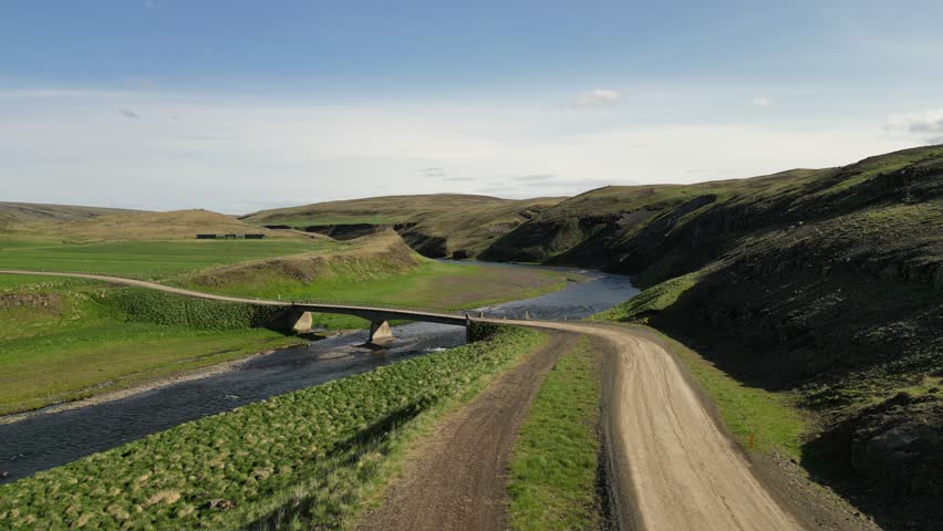 Scenic Bridge over River, A captivating aerial view of a rustic bridge gracefully spans a meandering river, carving its path through rolling hills in norway