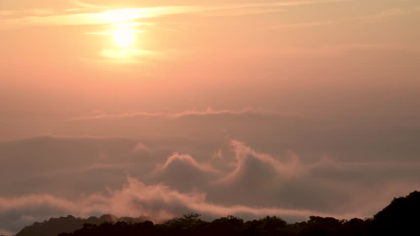 The sun dips below the horizon, casting a warm glow over the rolling hills of Datun Mountain in New Taipei City, Taiwan, during a beautiful twilight.