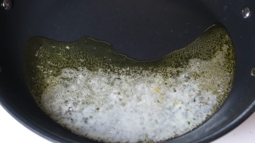 Adding white mushroom pieces to hot melted butter, and oil in black frying pan. 