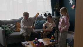 Wide shot of teenage kid with cerebral palsy and his sister playing with bubbles while their mother blowing them at home - Powered by Shutterstock - Get 15% off with code: PIKWIZARD15
