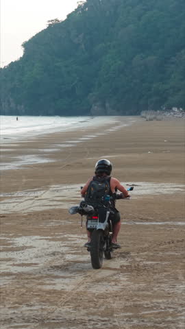 Motorcyclist riding on ao thung makham beach in chumphon, thailand