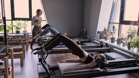 A group of woman exercises Glute bridge on a reformer bed machine in natural sunlight, focusing on pelvis and hips. - Powered by Shutterstock - Get 15% off with code: PIKWIZARD15