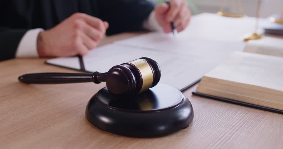Judge's gavel on workplace with male judge working in background. Male justice worker knocking mallet in courtroom having court verdict. Jurisdiction and legal law concept. 4k video.