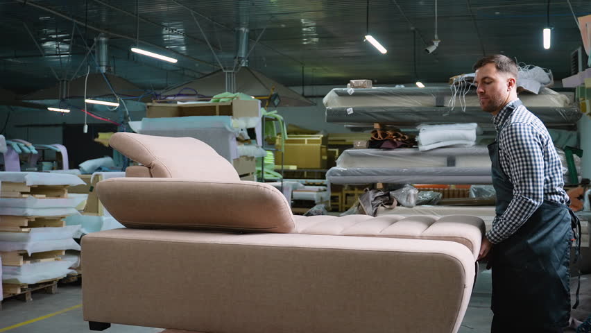 Man Testing Sofa Lift Mechanism in Furniture Workshop