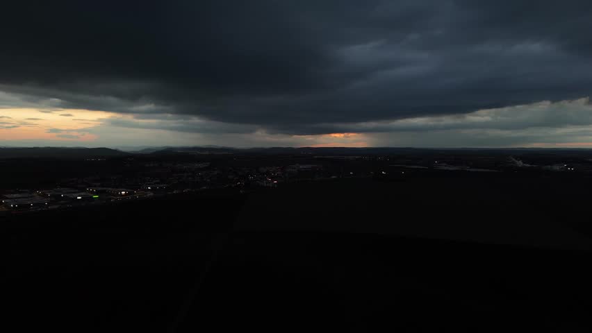 Dramatic drone footage of dark storm clouds descending over Prague. A moody aerial view of the historic city as the weather shifts, highlighting tension between nature and architecture.

