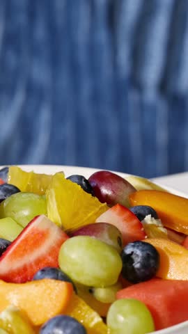bowl of fresh fruit salad on blue background, food closeup, healthy eating