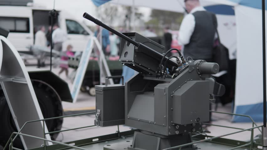 Specialists display advanced weapon systems and equipment at a military technology expo, featuring an array of modern defense innovations in an outdoor setting.