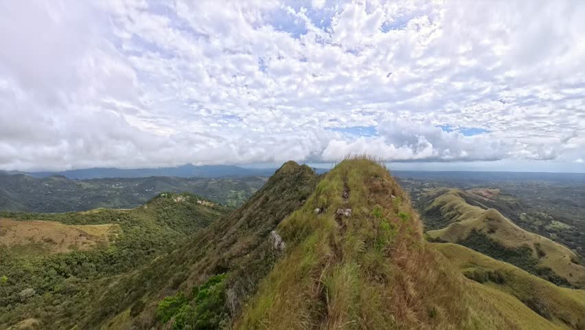 Mountain ridge with green hills and a dramatic sky covered in dense clouds at the summit viewpoint