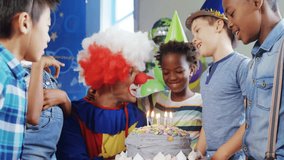 Clown carrying birthday cake into party room causing confetti burst and children blowing candles. Celebration, joy, festivity, cheer, milestone, entertainment, amusement - Powered by Shutterstock - Get 15% off with code: PIKWIZARD15