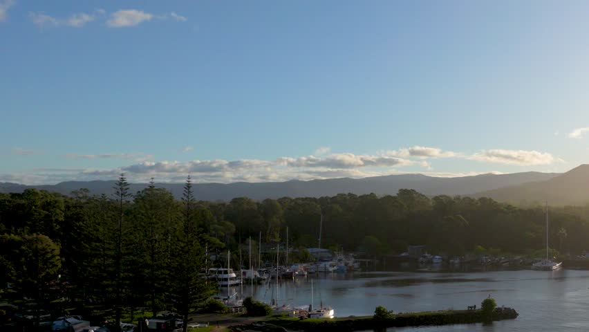 A tranquil sunset view over Brunswick Heads Marina, capturing calm waters and silhouetted trees under a clear sky