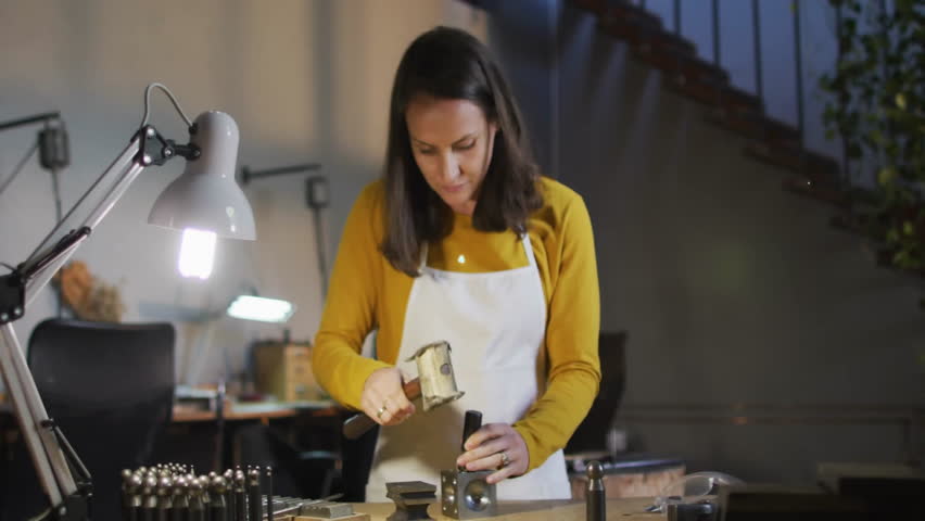 female crafter hammering metal piece in workshop initiating network icons showing tech connections. Artisan, craftsmanship, industrial, handmade, technology, innovation, focus - Powered by Shutterstock - Get 15% off with code: PIKWIZARD15