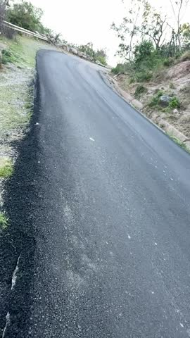 Curved road through elevated greenery with steep landscape sides, reflecting a remote, quiet, and untouched travel route in nature.