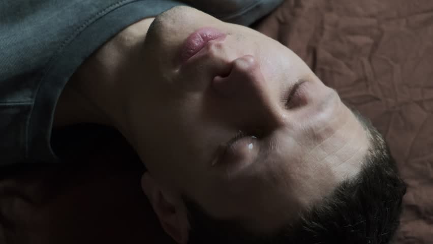 A blue-eyed young man cries. Close-up of man crying with tear rolling down cheek. A broken heart from unrequited love