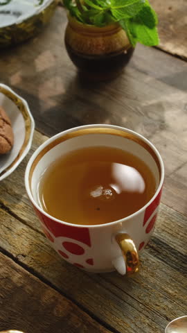 Vertical video. Drinking tea. Woman adding slice of lemon to mug of brewed green tea