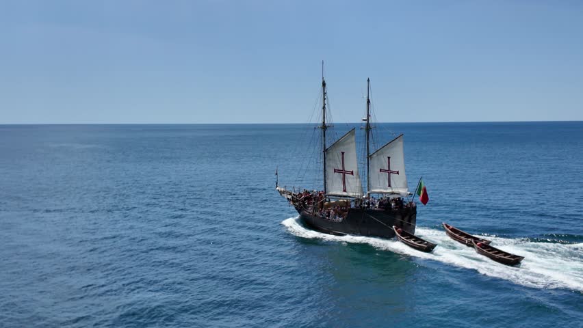 Replica of a Portuguese caravel sailing the ocean followed by three rowing boats in Portugal