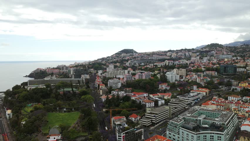 Cityscape of Funchal, Madeira, Portugal, showing buildings, harbor, hills and the Atlantic Ocean, offering a panoramic view of the city