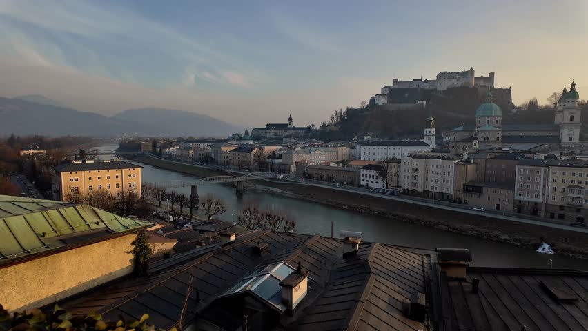 Salzburg, Austria: Pano of sunset over Salzburg medieval old town skyline with the Fortress Hohensalzburg, the Salzbach river and the gothic Cathedral dome and bell towers in Austria in the alps. 