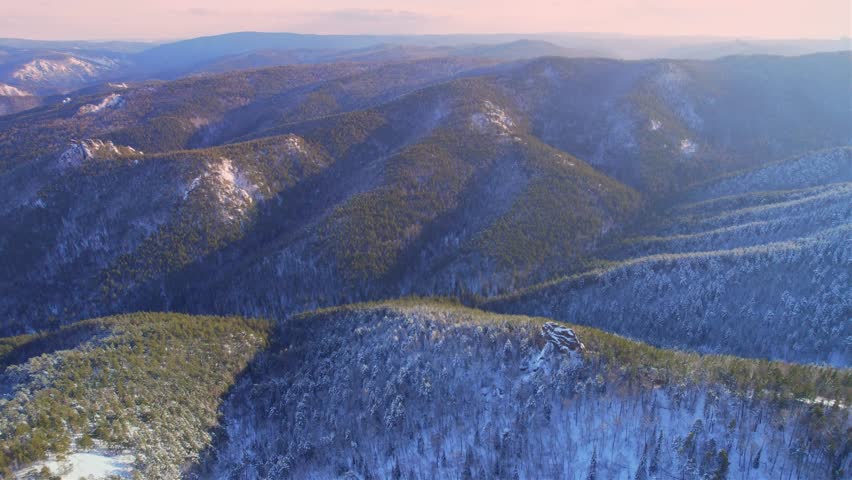 Majestic winter forest panorama unveiling against snowcapped mountains at sunset