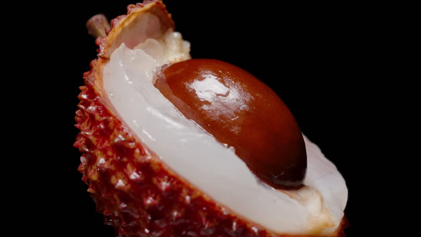 Close-Up of Slowly Rotating Lychee Showing Shiny Brown Seed Nestled in Translucent White Flesh with Red Textured Peel, Exotic Sweet Fruit Detail, Macro Nutrition Concept.
