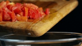 Freshly diced tomatoes being scraped from a wooden cutting board into a clear glass bowl, slow motion, hand held - Powered by Shutterstock - Get 15% off with code: PIKWIZARD15