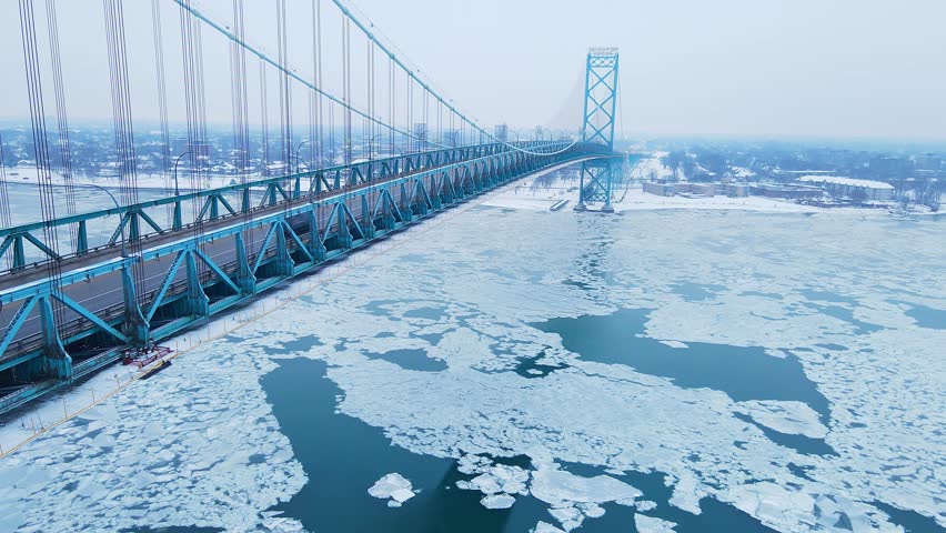 Ambassador Bridge stretches over icy Detroit River with heavy snow and frozen shoreline