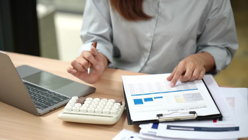 Accountant working at desk using calculator to calculate financial report in finance accounting business office concept