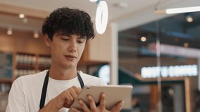 Portrait of focused guy waiter inputting order data on tablet computer in cafe. Positive man listens to guest choosing menu positions on device in cafeteria. Modern retail service - Powered by Shutterstock - Get 15% off with code: PIKWIZARD15