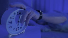 Young man trying to turn off a ringing alarm clock at morning. Close-up of hand reaching out to stop the alarm clock, to waking up at six o'clock - Powered by Shutterstock - Get 15% off with code: PIKWIZARD15