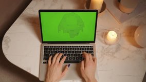 Top view of hands typing on laptop with green screen near candles, cozy workspace setup for screensaver or chroma key editing. - Powered by Shutterstock - Get 15% off with code: PIKWIZARD15