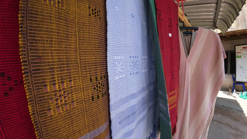 Traditional handwoven fabrics in various vibrant colors, displayed at a local farm in Chiang Mai, Thailand, highlighting intricate patterns and textures.
